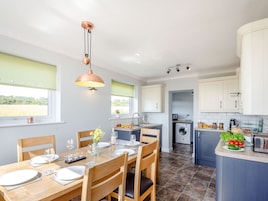 Una cocina moderna con comedor, que incluye una isla central, lavadora y vistas al exterior.