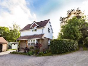 A two-story house with a sloped roof, a front porch, and a gravel driveway.