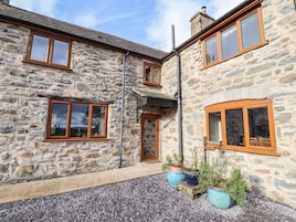 A stone building with multiple windows and a gravel driveway.