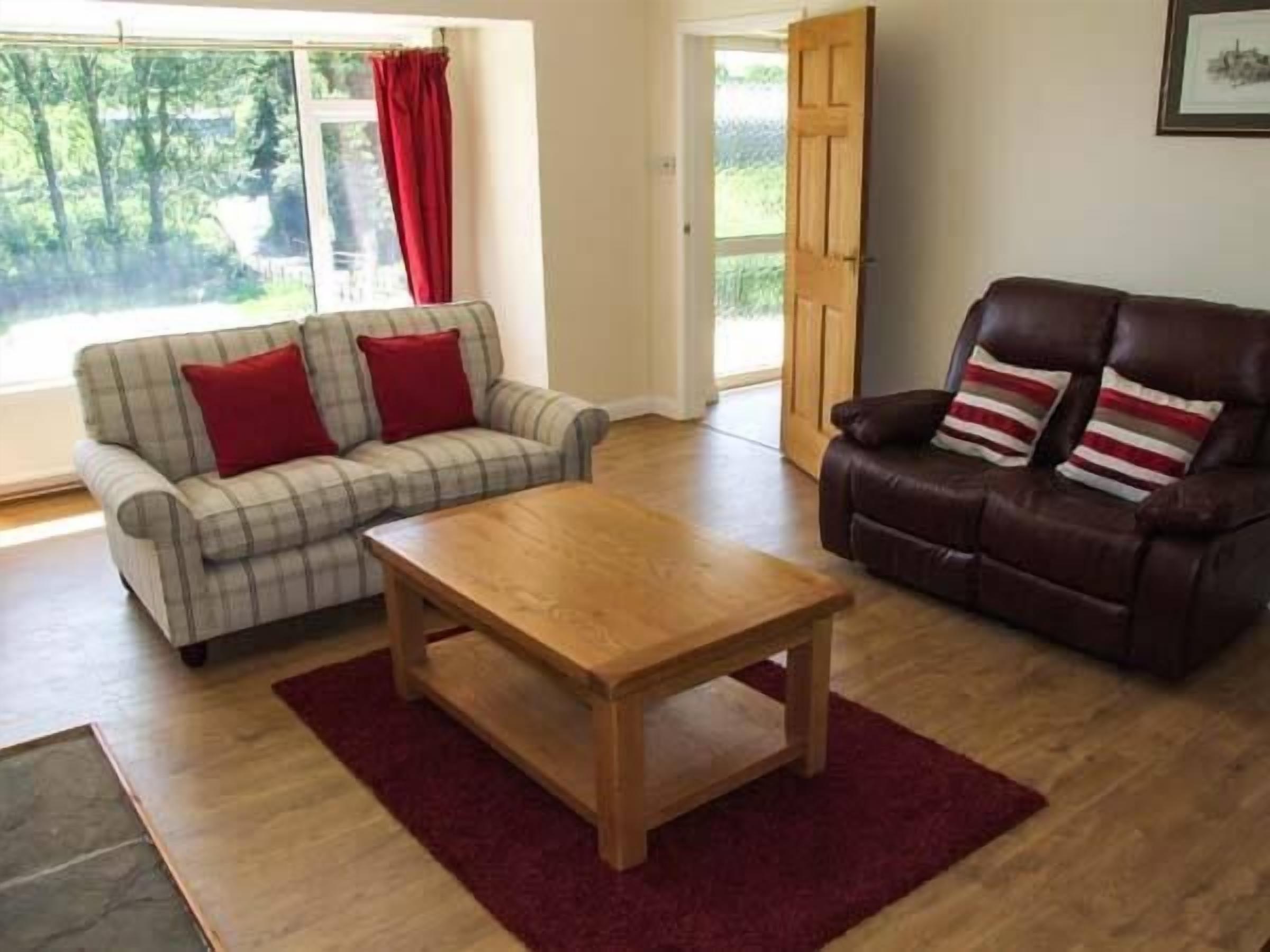 Ein Wohnzimmer mit einem Karomuster-Sofa, einem Ledersessel und einem Holztisch.