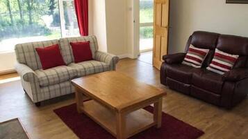 A living room with a plaid sofa, a leather armchair, and a wooden coffee table.