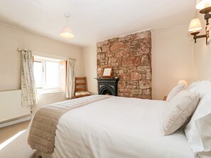 A bedroom with a large bed, a stone fireplace, a window with curtains, and a wooden chair. - Gordon's View (Newnham)