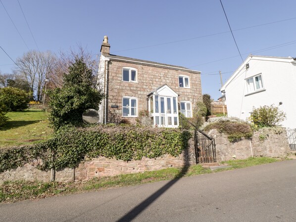 A two-story stone house with a brick facade, white window frames, and a small garden area. - Gordon's View (Newnham)