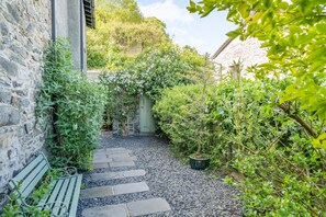 A stone pathway leading to a rustic building surrounded by lush greenery. - 2 Beacon High (Grange-over-Sands)