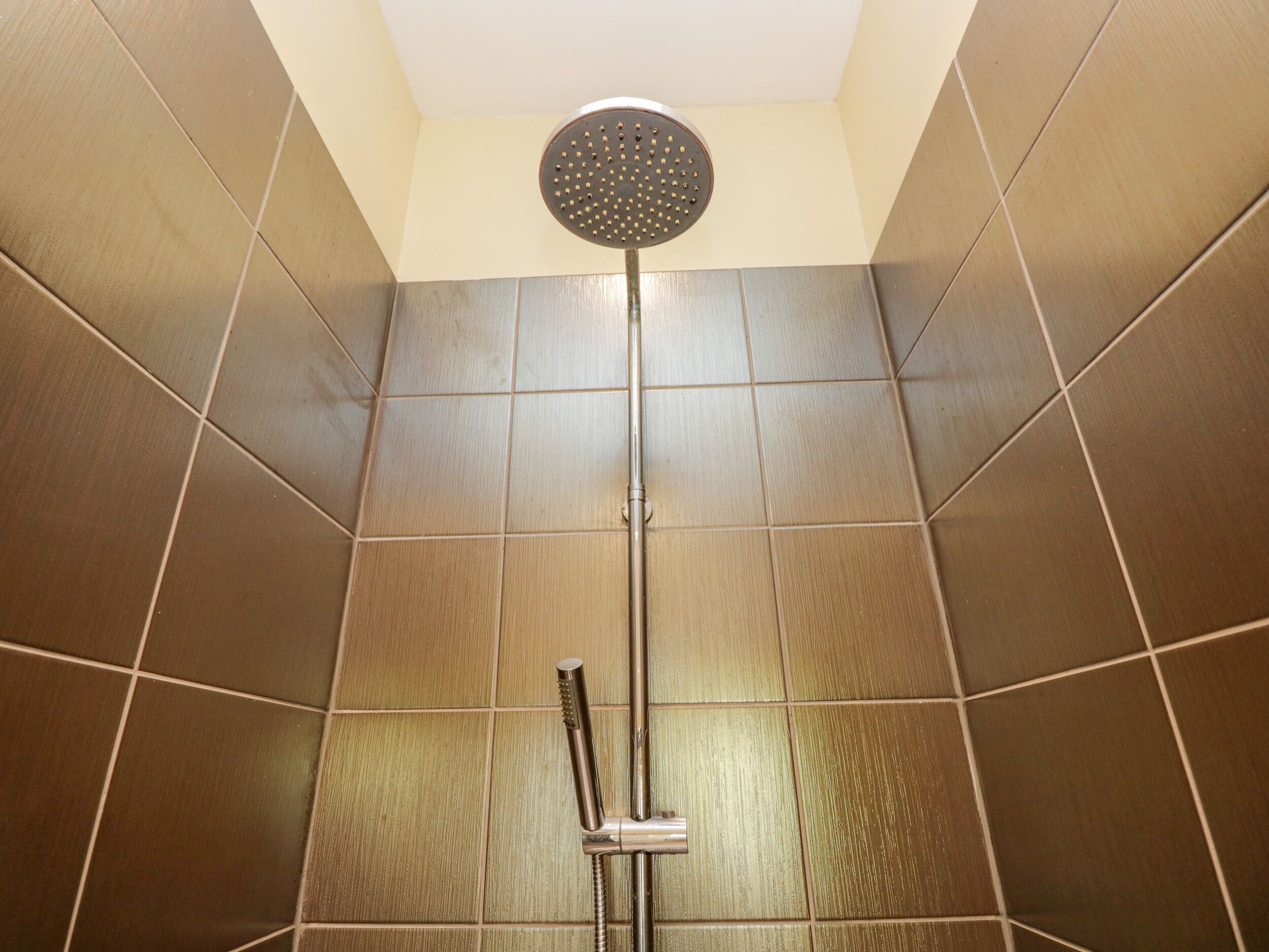 A shower with a round head and a handheld showerhead.