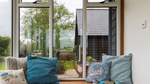 A view through a window with a wooden bench, pillows, and a cup. - Farley Lodge (Salisbury)