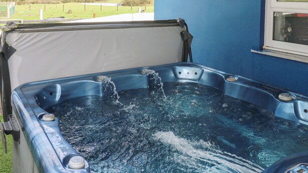 Un jacuzzi con agua, una pared azul y una ventana.