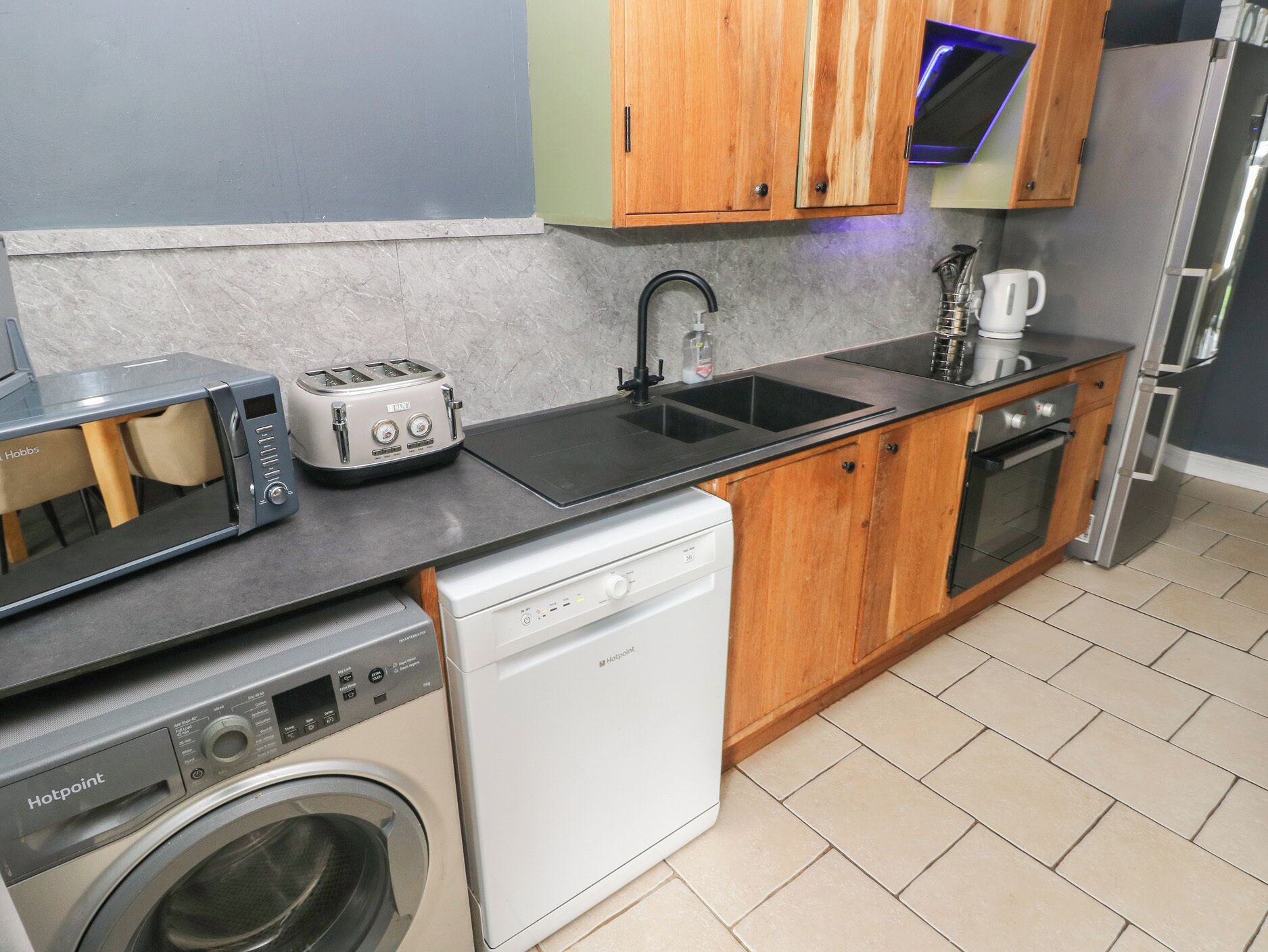 A compact kitchen with a washing machine, a toaster, a sink, and a microwave.
