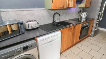 A compact kitchen with a washing machine, a toaster, a sink, and a microwave.