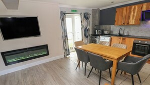 Una cocina moderna con un televisor de pantalla plana, un acuario integrado y una zona de comedor con una mesa y sillas de madera.