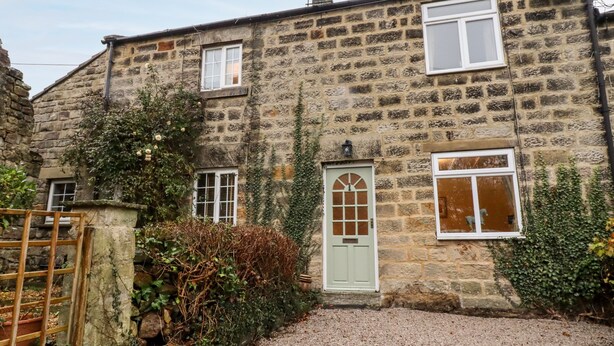 A stone house with a gravel driveway, a wooden gate, and a small garden area. - 7 Scarah Bank Cottages (Harrogate)
