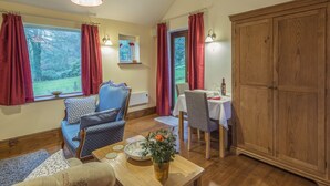 A cozy room with a sofa, chairs, a dining table, and a large wooden cabinet. - Woodpeckers Cottage (Church Stretton)