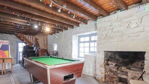 A billiards table in a rustic room with a stone wall and wooden beams. - 1 Seafield Street (Buckie)