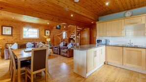 A wooden cabin interior with a dining area, kitchen, and a spiral staircase. - Jamaal Lodge (Morpeth)