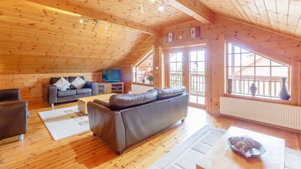 A wooden interior with a sofa, a TV, and a dining table. - Jamaal Lodge (Morpeth)