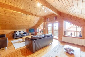 A wooden interior with a sofa, a TV, and a dining table. - Jamaal Lodge (Morpeth)