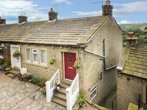 A stone house with a red door, a front porch with steps, and potted plants. - Ginnel Corner (Huddersfield)
