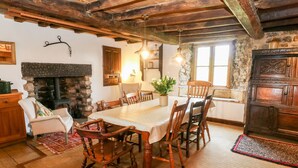 A rustic dining area with a large wooden table, several chairs, a stone fireplace, and a wooden ceiling. - Wray Green (Kirkby Stephen)