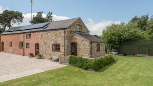 A stone building with a sloped roof, a gravel driveway, and a well-maintained lawn. - Hope Hall Barn (Shrewsbury)