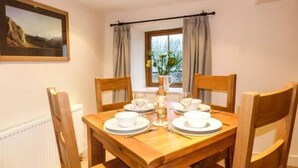 Un coin repas avec une table en bois dressée pour quatre personnes, entourée de chaises en bois.