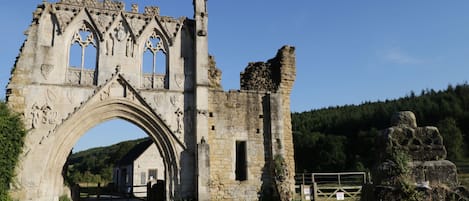 A historic stone archway with intricate carvings and a tall, narrow tower to the right.
