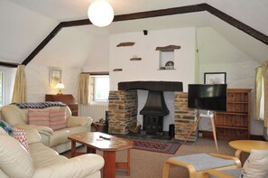 A cozy living room with a stone fireplace, a television, and a comfortable seating area.