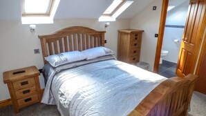 A bedroom with a wooden bed, a nightstand, a wooden wardrobe, and a skylight. - Corner Croft (Buxton)