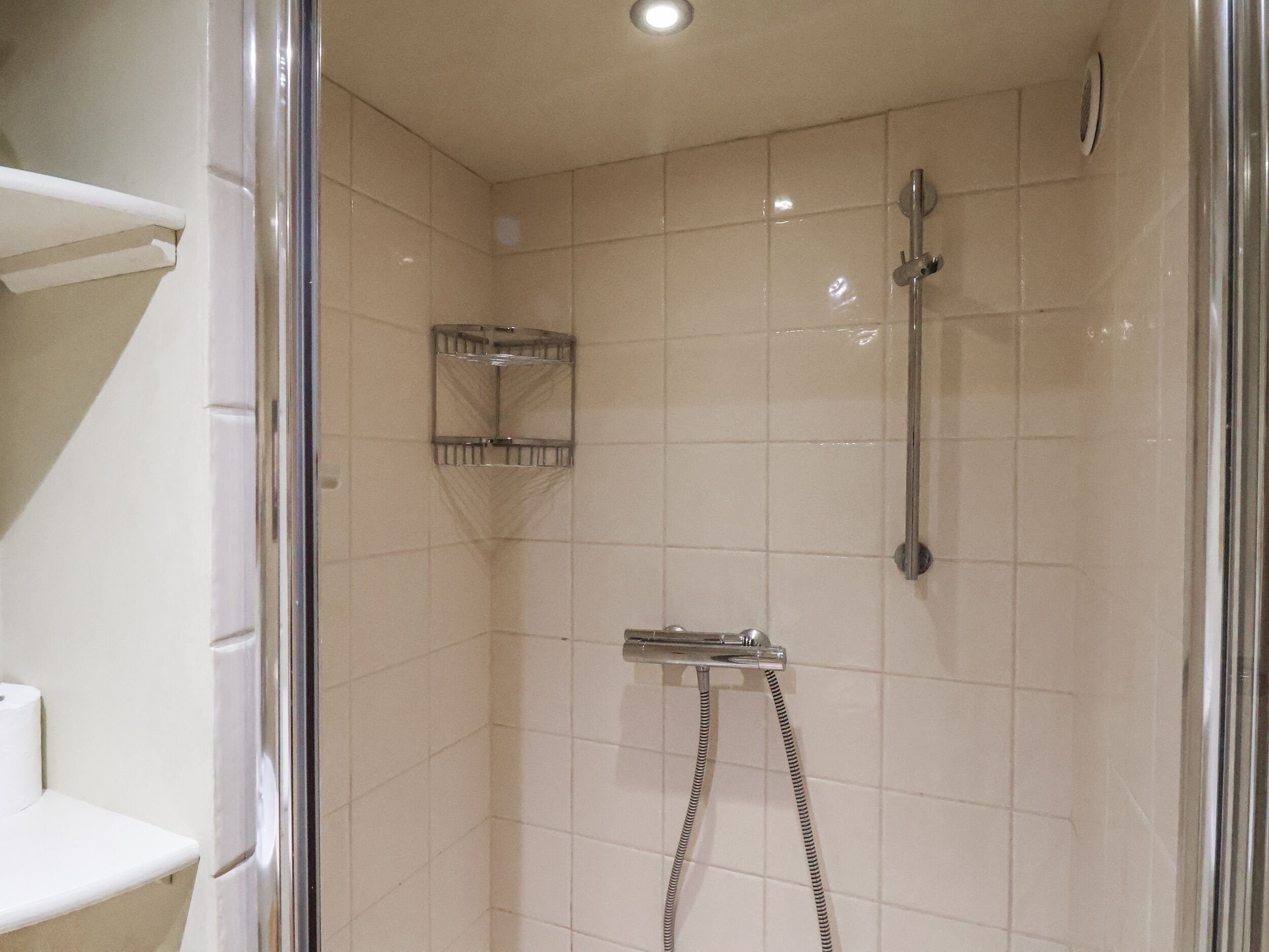 Une douche équipée d’un pommeau de douche à main et d’un robinet fixé au mur.