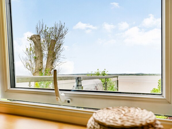 A view from a window overlooking a river with a wooden railing and a woven basket on the windowsill. - Solway Cottage (Wigton)