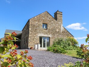 A stone building with a pitched roof, a chimney, and a gravel driveway leading to a glass door entrance. - Cottam Cottage Farm (Preston)