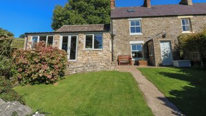 A stone house with a garden, a wooden bench, and a clear blue sky. - Hoodgill Barn (Barnard Castle)