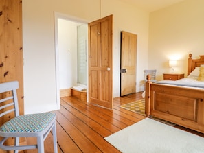 Relax in this serene bedroom with a large bed, comfortable chair, and a bedside table.