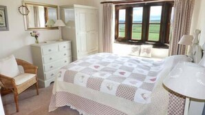 A bedroom with a bed, dresser, chair, and a window with a view of the outdoors. - Street Head Farm (Keighley)