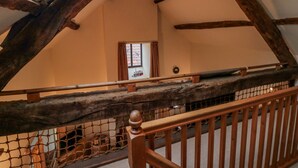 A wooden staircase with a net barrier, leading to a room with a window and a door. - Dairy House (Pickering)