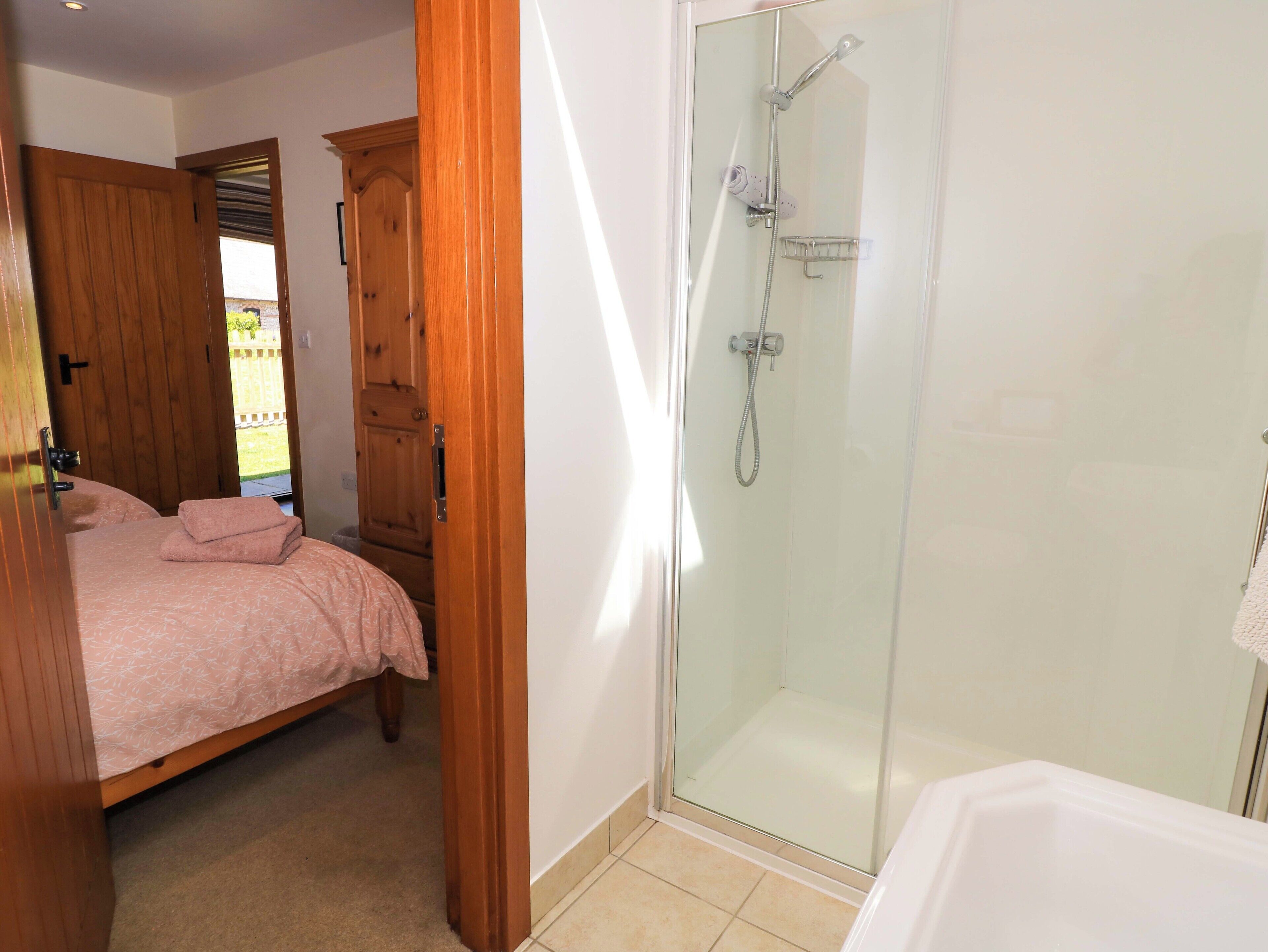 Un dormitorio con cama, armario de madera y zona de ducha con cristal.