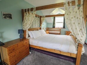 Une chambre à coucher avec un lit en bois, une table de chevet, une commode et une fenêtre avec des rideaux.