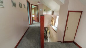 Ein Flur mit Teppichboden, Holztürrahmen und einer Treppe, die in eine obere Ebene führt.