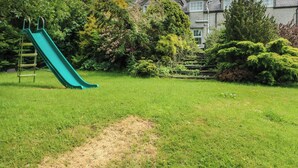 A grassy area with a green slide and a wooden staircase leading to a house. - Glan y Gors (Caernarfon)