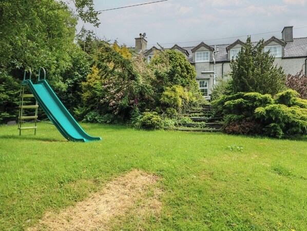 A grassy area with a green slide and a wooden staircase leading to a house. - Glan y Gors (Caernarfon)