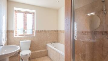 A bathroom with a toilet, sink, bathtub, and shower.