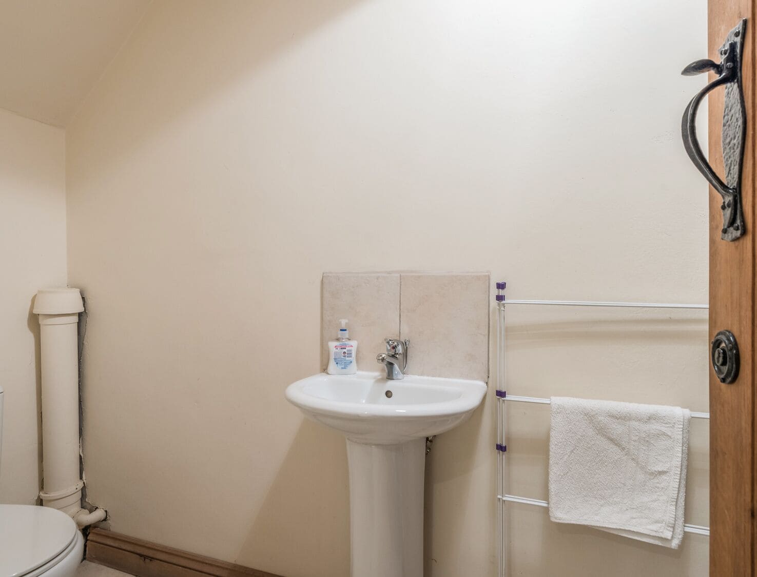 A bathroom with a white sink, a toilet, and a towel rack.