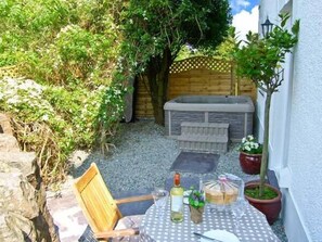 Enjoy a romantic dinner for two in this secluded outdoor space, complete with a table set and a hot tub nearby.