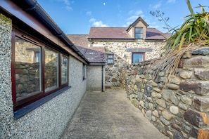 Pathway leads to a traditional stone building with a window.