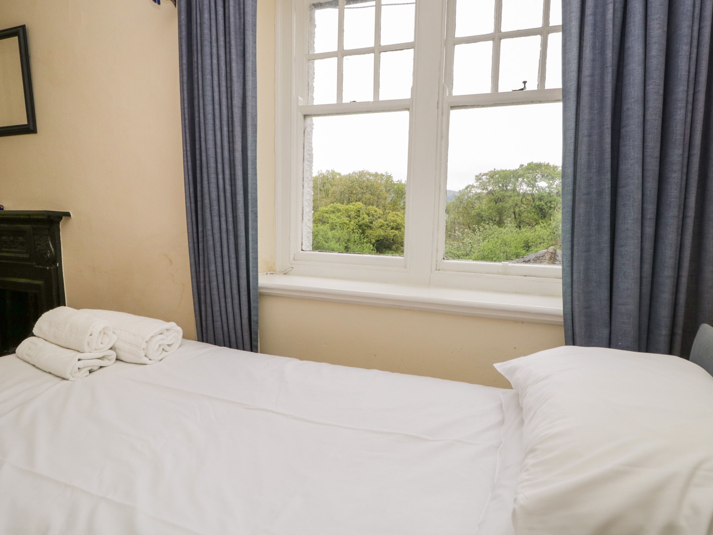 Une chambre d’hôtel avec un lit, une commode et une fenêtre avec des rideaux.