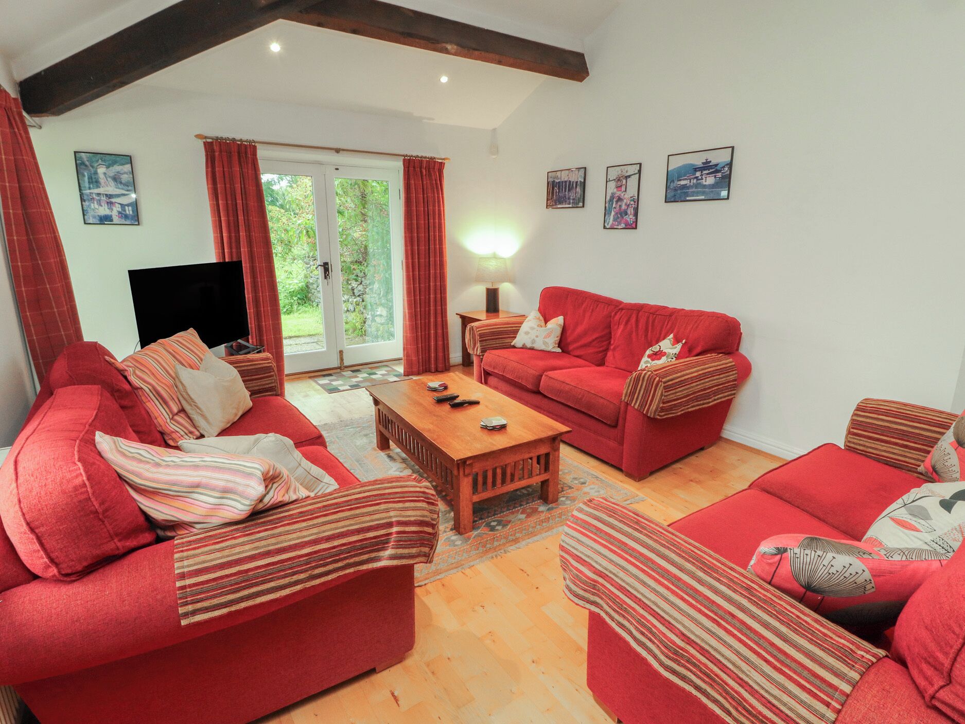 A living room with red sofas, a wooden coffee table, and a TV.