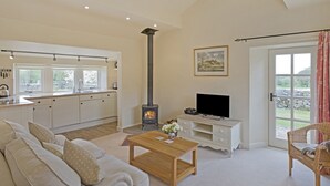 A spacious living area with a fireplace, a television, and a comfortable seating area. - Reynard Ing Cottage (Ilkley)