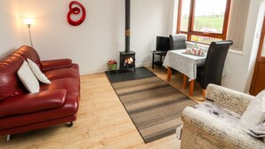 Ein gemütliches Wohnzimmer mit einem roten Ledersofa, einem schwarzen Kamin und einem Essbereich mit Tisch und Stühlen.
