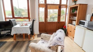 Ein gemütliches Wohnzimmer mit Esstisch, Sofa und Küchenzeile mit Mikrowelle und Schränken.