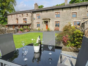A stone building with a well-maintained lawn and a table set for dining.