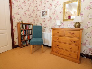 A room with a bookshelf, a chair, a dresser, and a mirror on the wall. - Barnbrook (Leyburn)